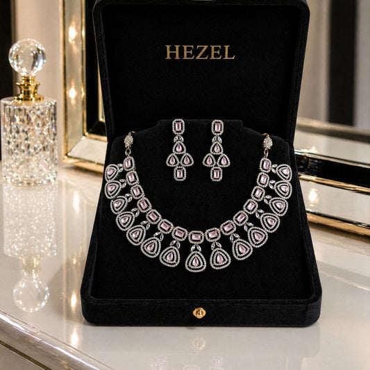 Elegant HEZEL statement necklace featuring teardrop pink gemstones and diamond-style detailing, paired with matching earrings on a premium black display.