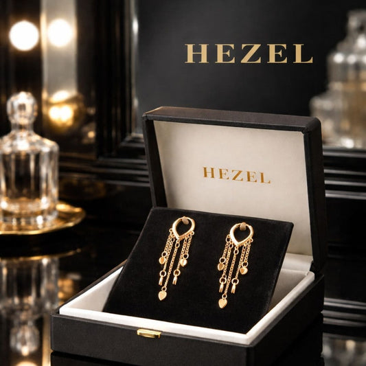 “Hezel gold heart tassel earrings with delicate chain drops displayed in premium black luxury jewelry gift box with elegant vanity background”