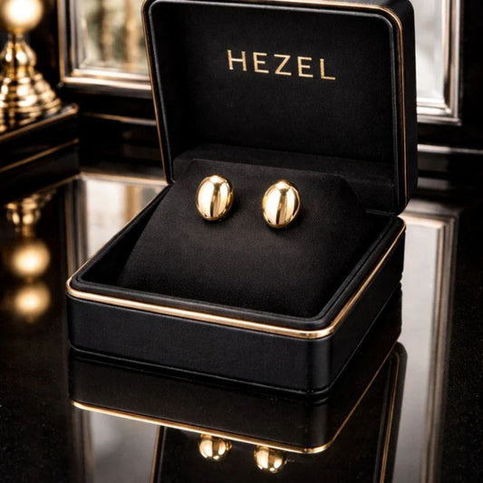 Hezel polished gold stud earrings in a luxury black velvet jewelry box with elegant reflective background