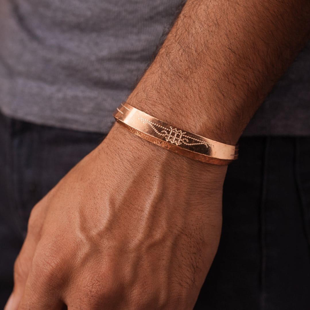 Minimalist gold bangle worn on wrist, featuring fine engraved detailing for a sleek and modern look