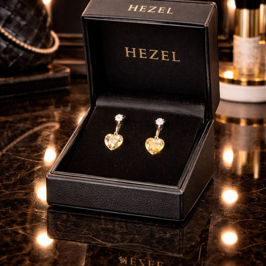 Elegant heart-shaped gold drop earrings by Hezel, displayed in a premium black jewelry box with a luxurious setting