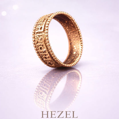 HEZEL rose gold textured band ring with intricate geometric engraving on reflective surface with soft gradient background