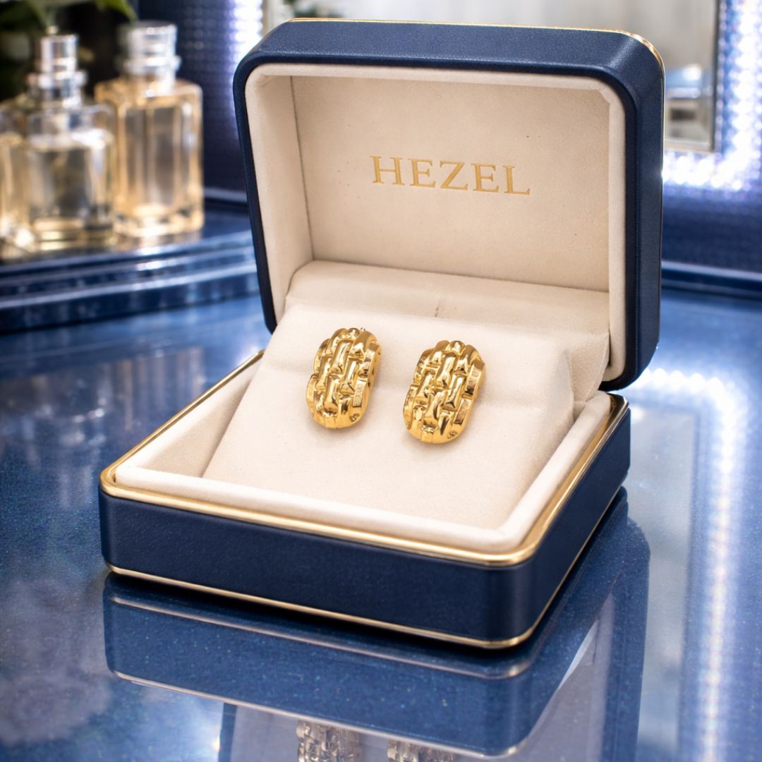 Gold textured oval stud earrings displayed in a premium navy blue HEZEL jewelry box with soft interior