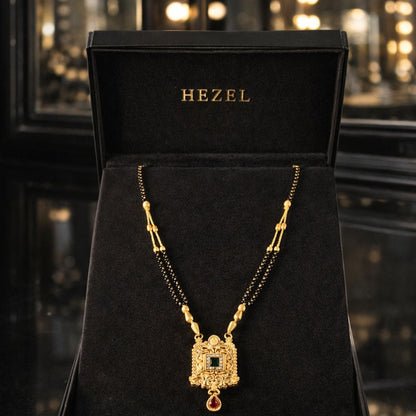 HEZEL traditional gold mangalsutra with elegant black beads and royal pendant showcased in a premium black velvet jewelry box with luxury festive background