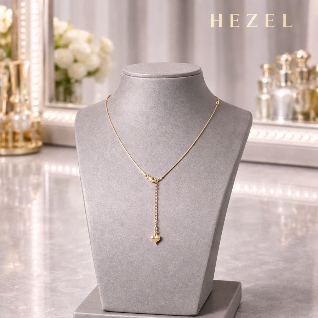 HEZEL gold heart drop necklace on grey velvet stand with luxury background