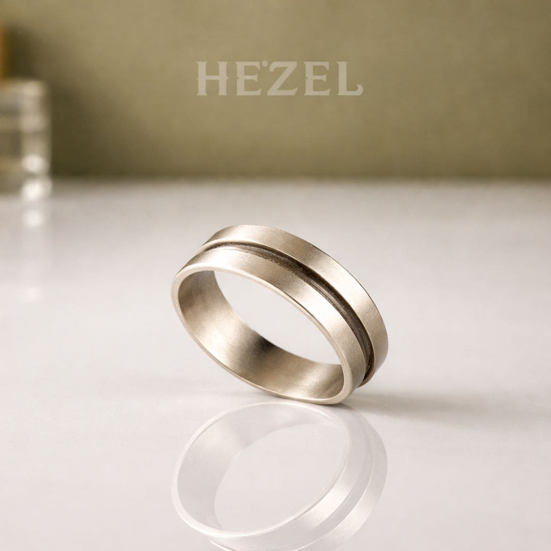 HEZEL minimalist silver band ring with textured center stripe on reflective surface with soft neutral background