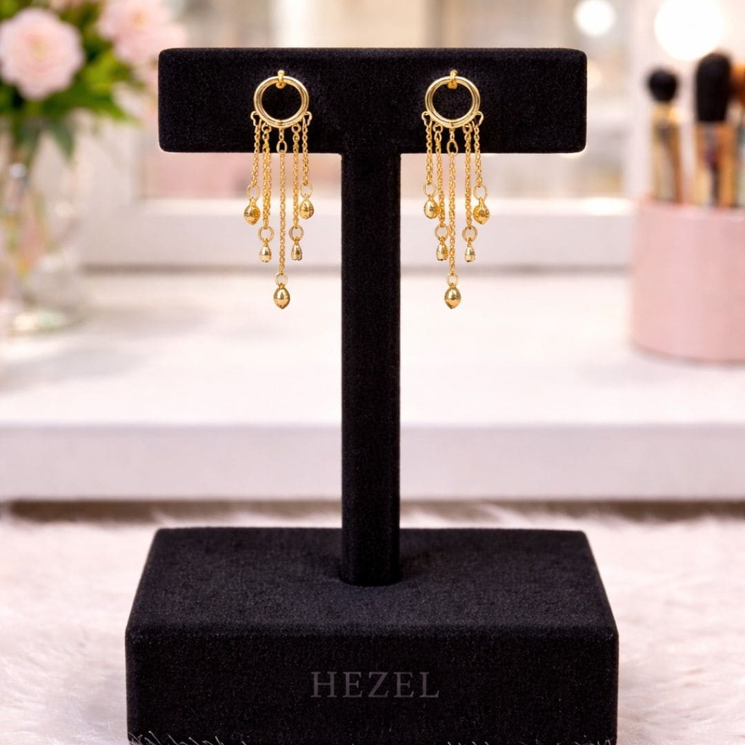 “Hezel gold hoop tassel earrings with delicate chain drops displayed on premium black velvet jewelry stand in elegant vanity setting