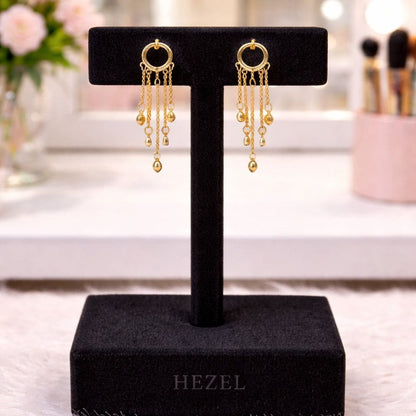 “Hezel gold hoop tassel earrings with delicate chain drops displayed on premium black velvet jewelry stand in elegant vanity setting