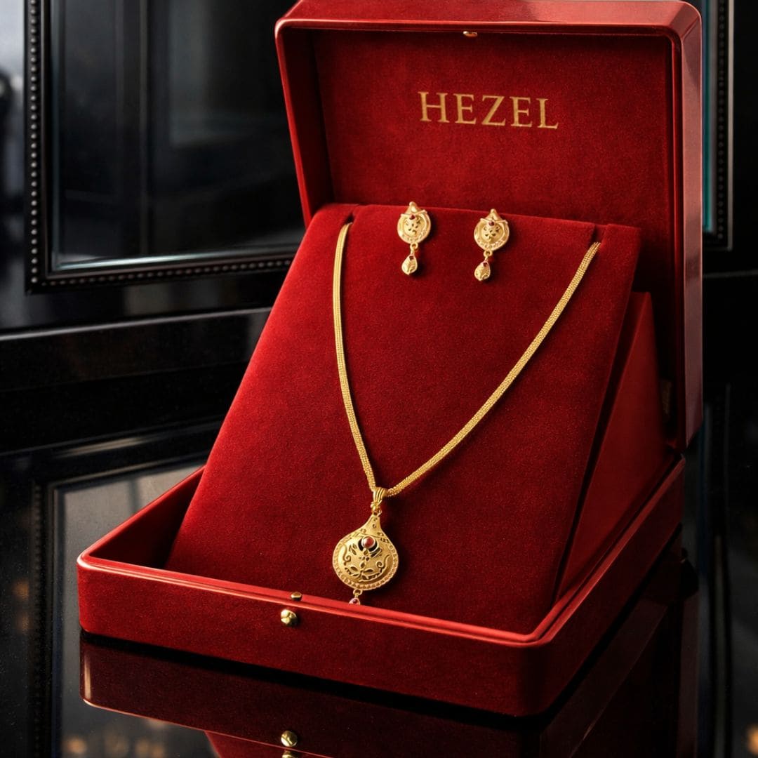 HEZEL gold-tone pendant necklace and matching earrings set displayed in a luxurious red velvet jewelry box with premium reflective background