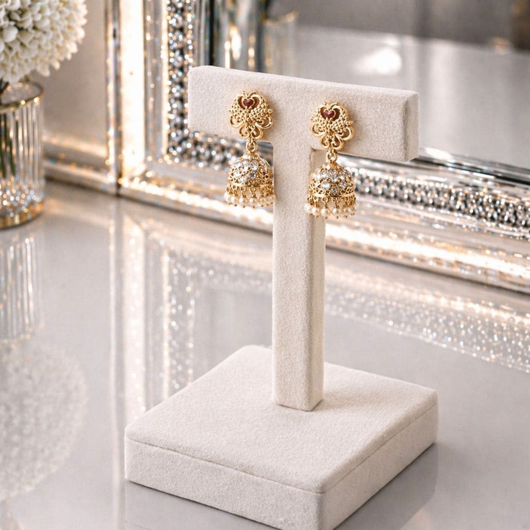 HEZEL gold-tone jhumka earrings with pearl drops and intricate filigree detailing, presented in a luxury black velvet jewellery box.