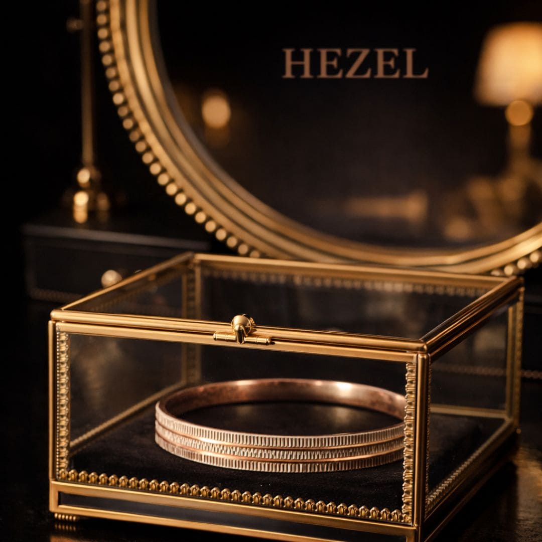 Hezel gold bangle elegantly displayed in a glass jewelry box with a luxurious warm-toned backdrop