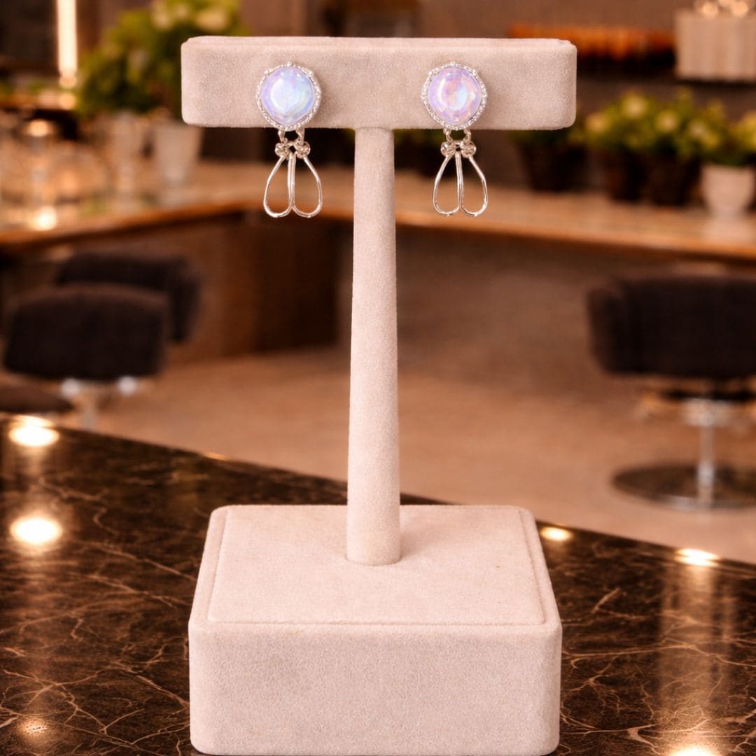 Hezel elegant silver drop earrings with iridescent round stones displayed on beige velvet stand in luxury settin