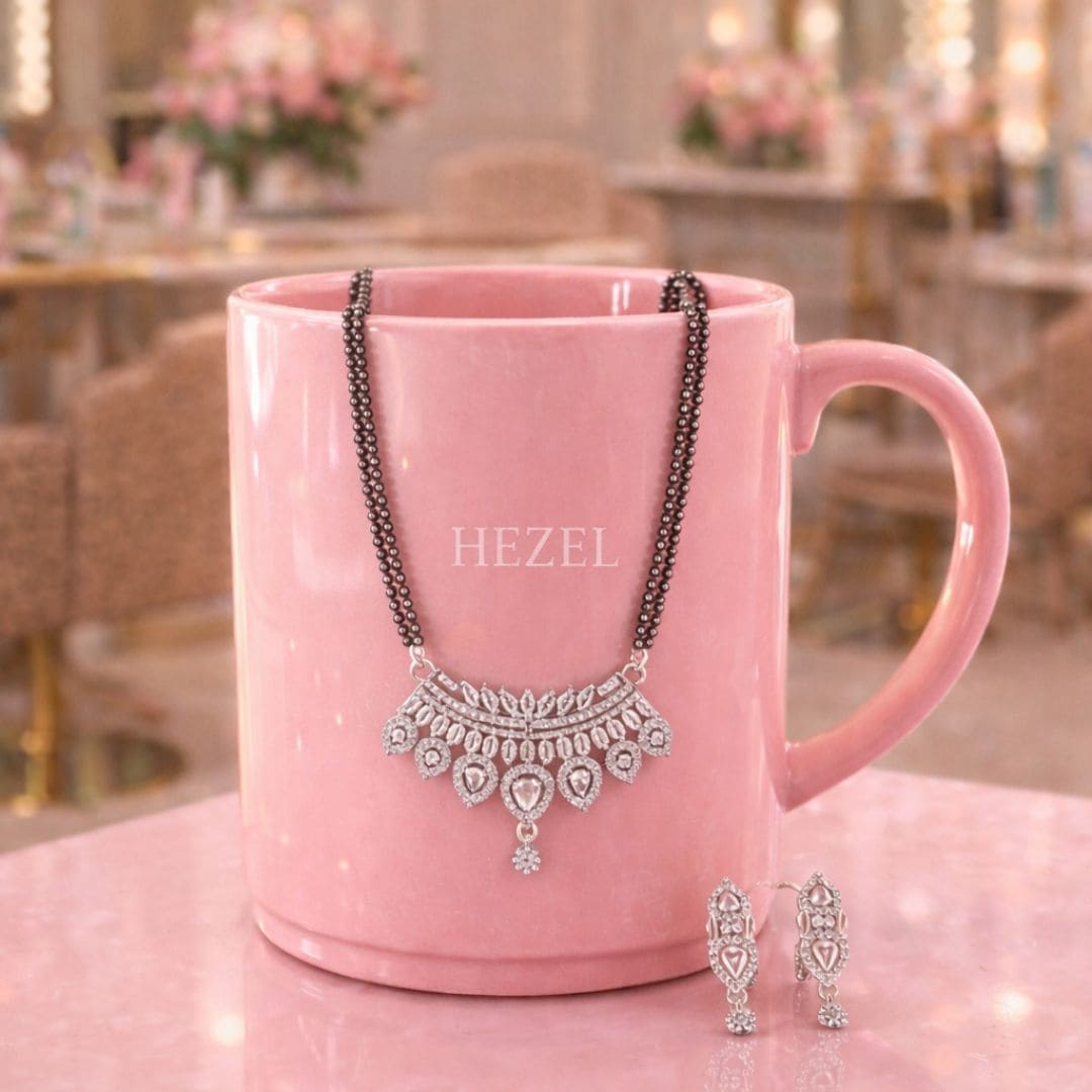 Hezel black bead necklace set with silver pendant and matching earrings displayed on elegant pink mug.