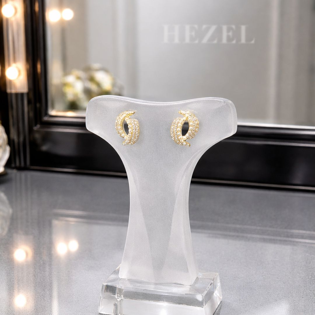 HEZEL gold zircon stud earrings displayed on premium jewelry stand with elegant background