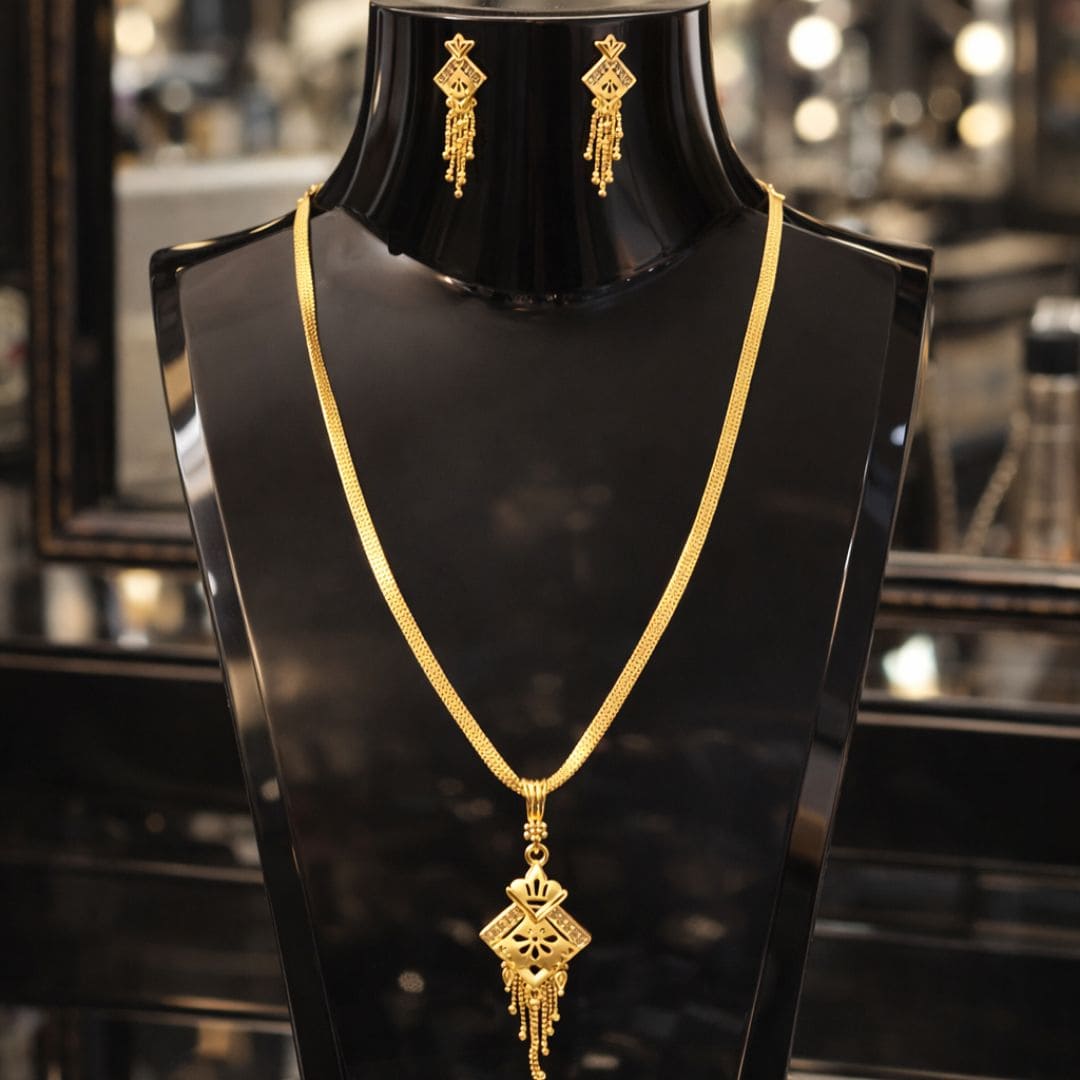 HEZEL gold-tone necklace and earrings set on a glossy black stand with a luxurious boutique background.