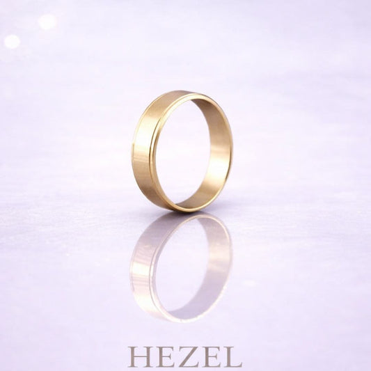 HEZEL minimalist gold band ring displayed on a soft reflective surface with a clean, elegant background, highlighting a timeless and refined desig