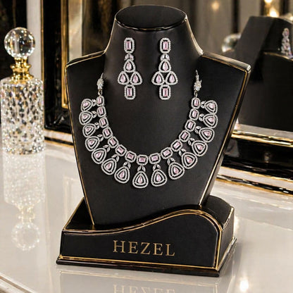 Luxury HEZEL pink stone necklace set with matching drop earrings displayed on a glossy black jewellery stand with gold accents.