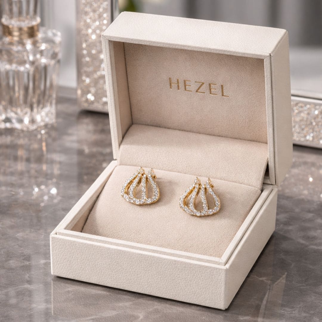 Hezel gold stud earrings with crystal detailing, elegantly presented in a premium beige jewelry bo