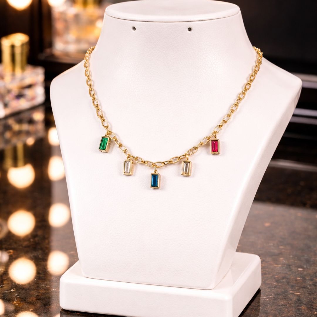 HEZEL gold charm necklace with colorful gemstone pendants displayed on a white jewelry stand