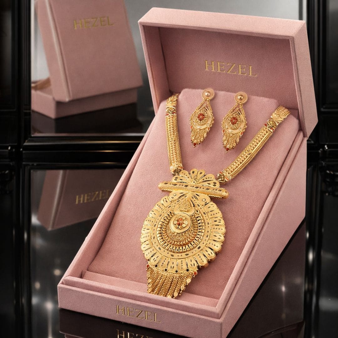 Elegant gold statement necklace set with intricate traditional design and matching earrings, displayed in a premium HEZEL pink jewelry box.