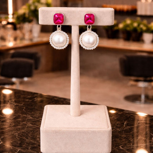 “Red gemstone and pearl drop earrings displayed on elegant beige jewelry stand