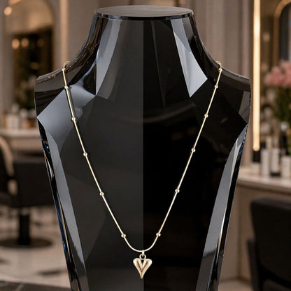 HEZEL gold heart pendant necklace with delicate chain displayed on a luxury black mannequin