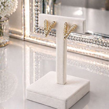 HEZEL luxury gold earrings on premium white velvet display stand with elegant mirror background