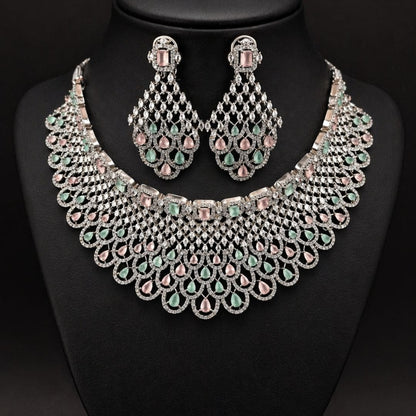Hezel statement necklace set with pastel green and pink stones, paired with matching chandelier earrings on a black display