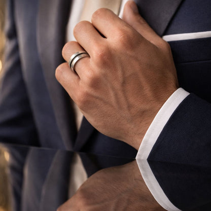 HEZEL minimalist silver band ring with dual stripe design worn by male model in formal suit close-up with reflective surfac