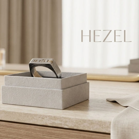 Minimalist silver signet ring displayed on beige jewelry box with Hezel branding