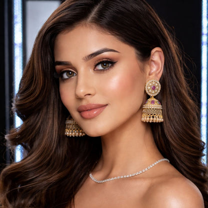 Professional portrait of a woman wearing traditional gold jhumka earrings with ruby accents from Hezel, styled in a luxury studio setting.