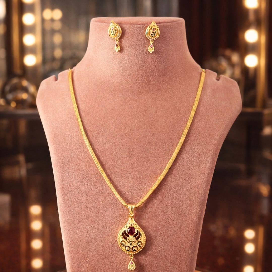 Elegant HEZEL gold-tone pendant necklace with matching earrings showcased on a premium velvet display stand with warm luxury lighting background.