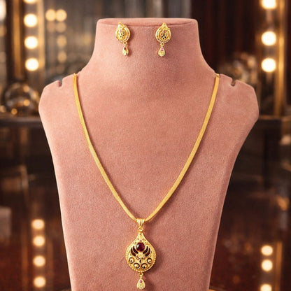 Elegant HEZEL gold-tone pendant necklace with matching earrings showcased on a premium velvet display stand with warm luxury lighting background.