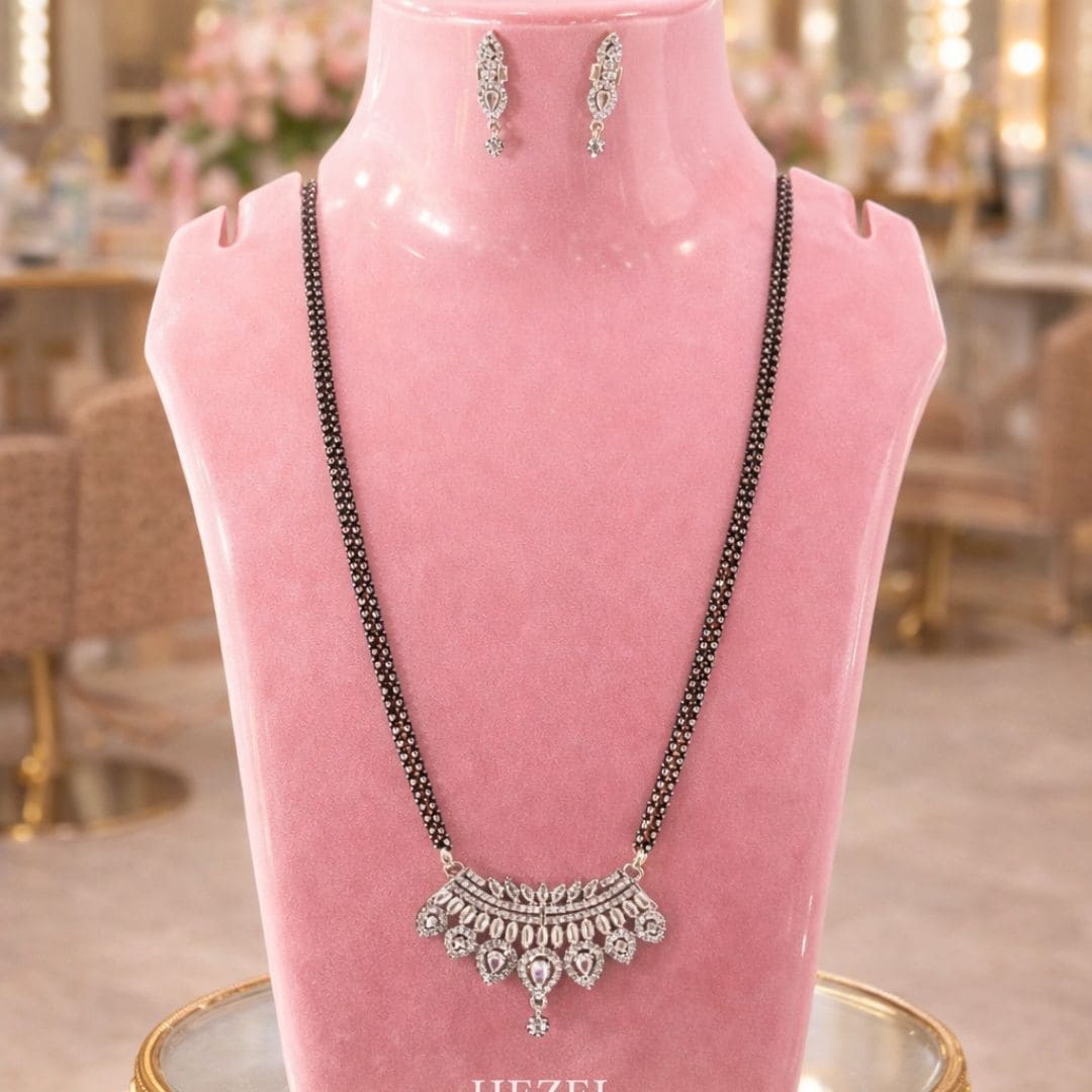Hezel black bead necklace with silver floral pendant and matching earrings on elegant pink display stand.