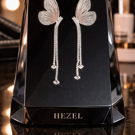 Hezel butterfly design long drop earrings with crystal detailing displayed on black stand