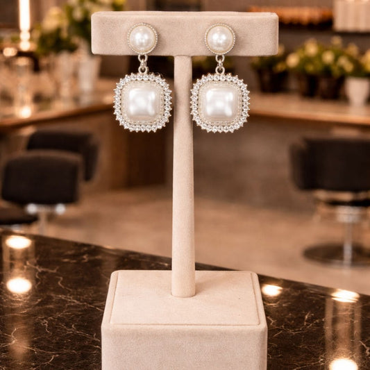 Hezel luxury pearl drop earrings with square halo design displayed on elegant velvet stand in premium boutique setting