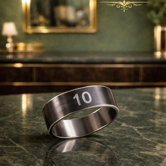 Hezel brand minimalist stainless steel band ring engraved with “10,” displayed on a glossy marble surface in a warm, luxurious interior setting.